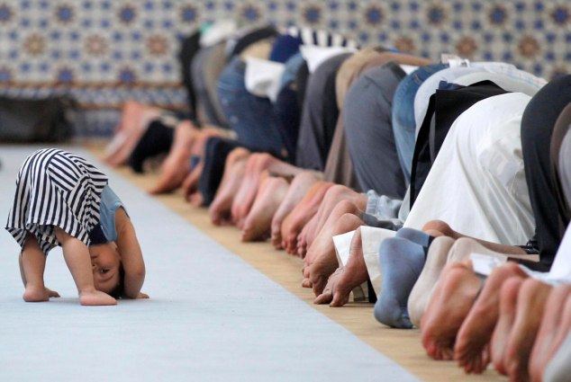 A child is seen near members of the Muslim community attending midday prayers at Strasbourg Grand Mosque in Strasbourg